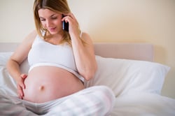 Pregnant woman having phone call at home